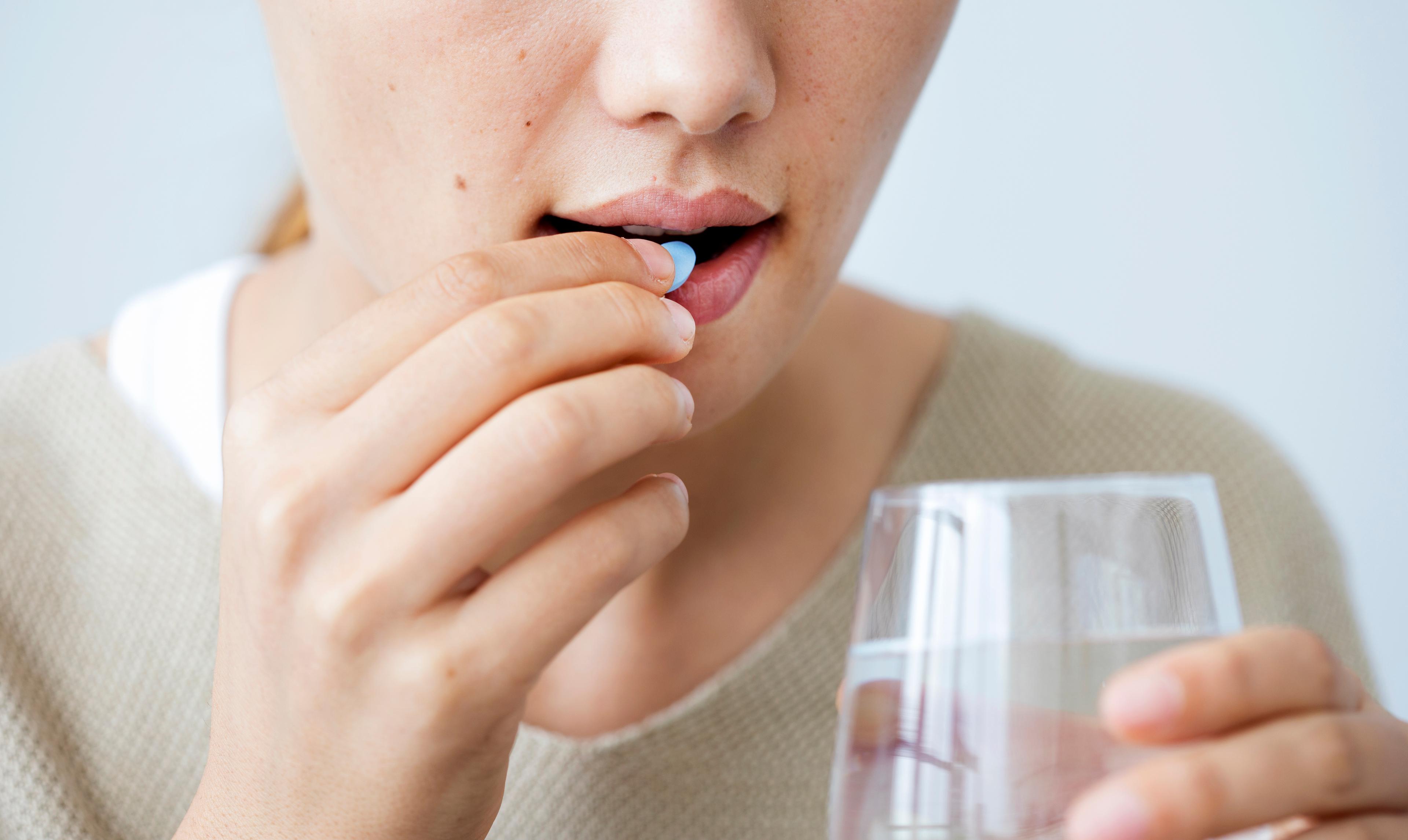 Woman taking a pill with a glass of water